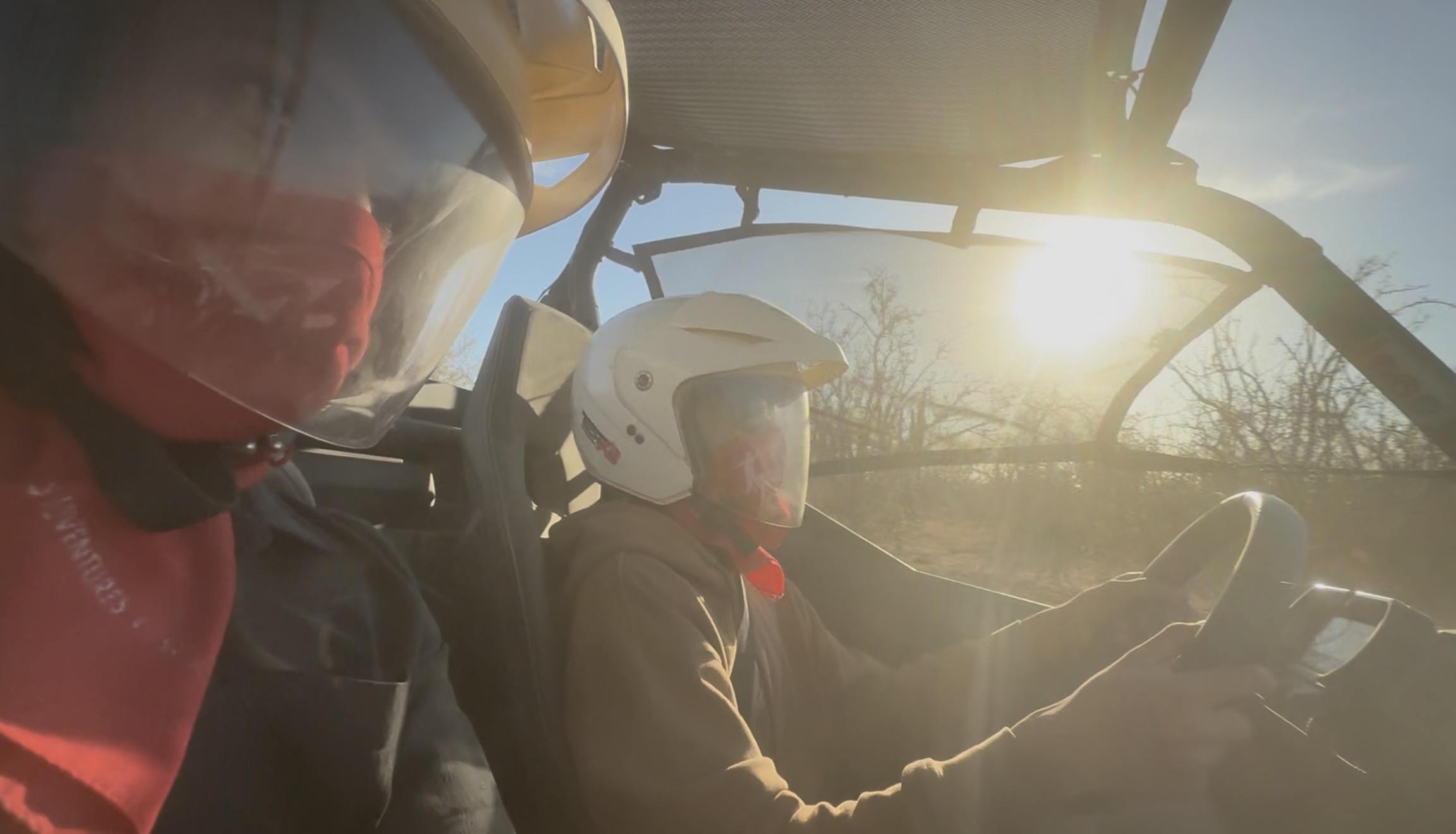 Two riders with helmets inside UTV with sun flare in Los Cabos