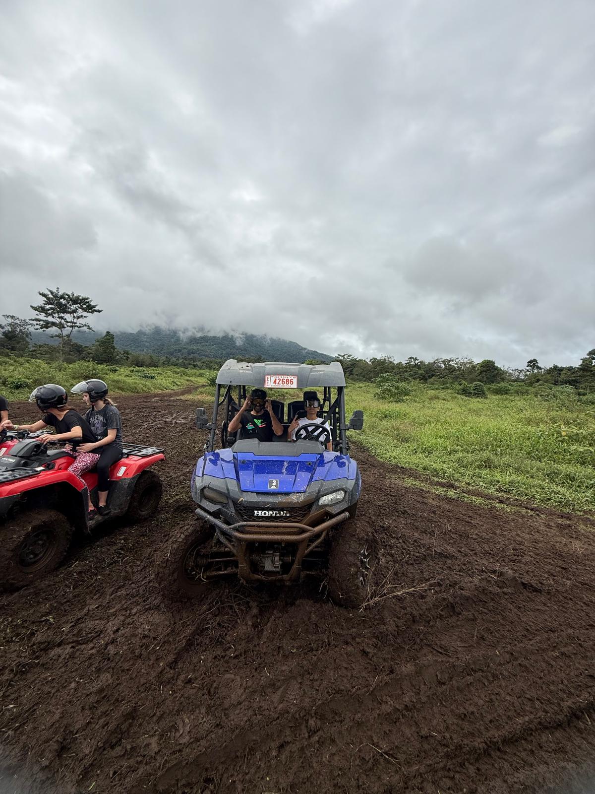 UTV stuck in mud with ATVs on a lush green Costa Rican trail