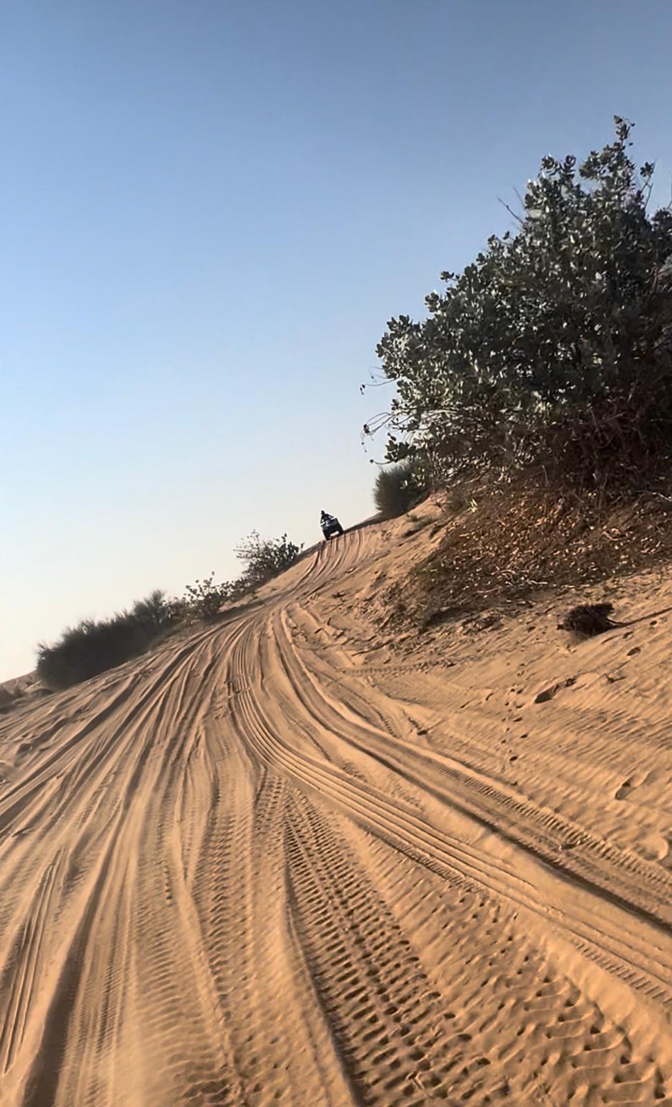 ATV climbing a golden sand dune in Dubai desert