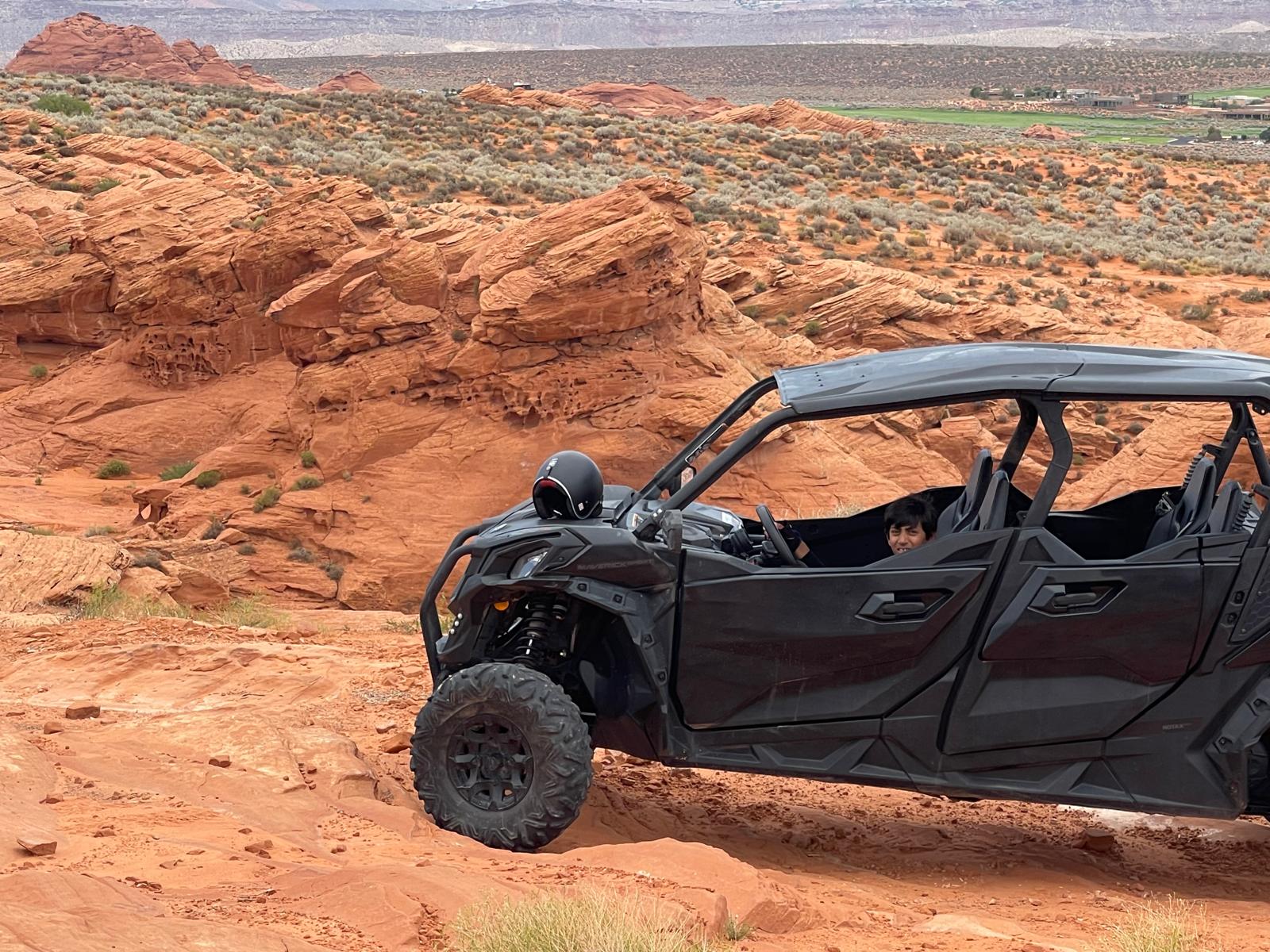 UTV parked on red rock cliff with scenic canyon views